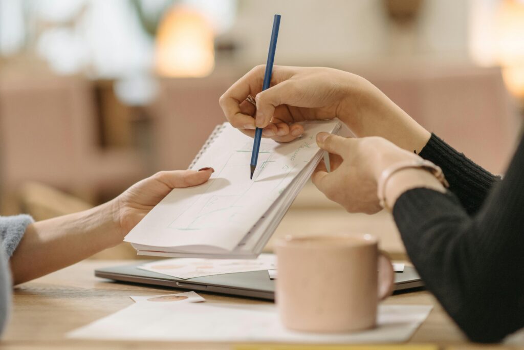 Close-up of hands collaborating on sketches during a business meeting.